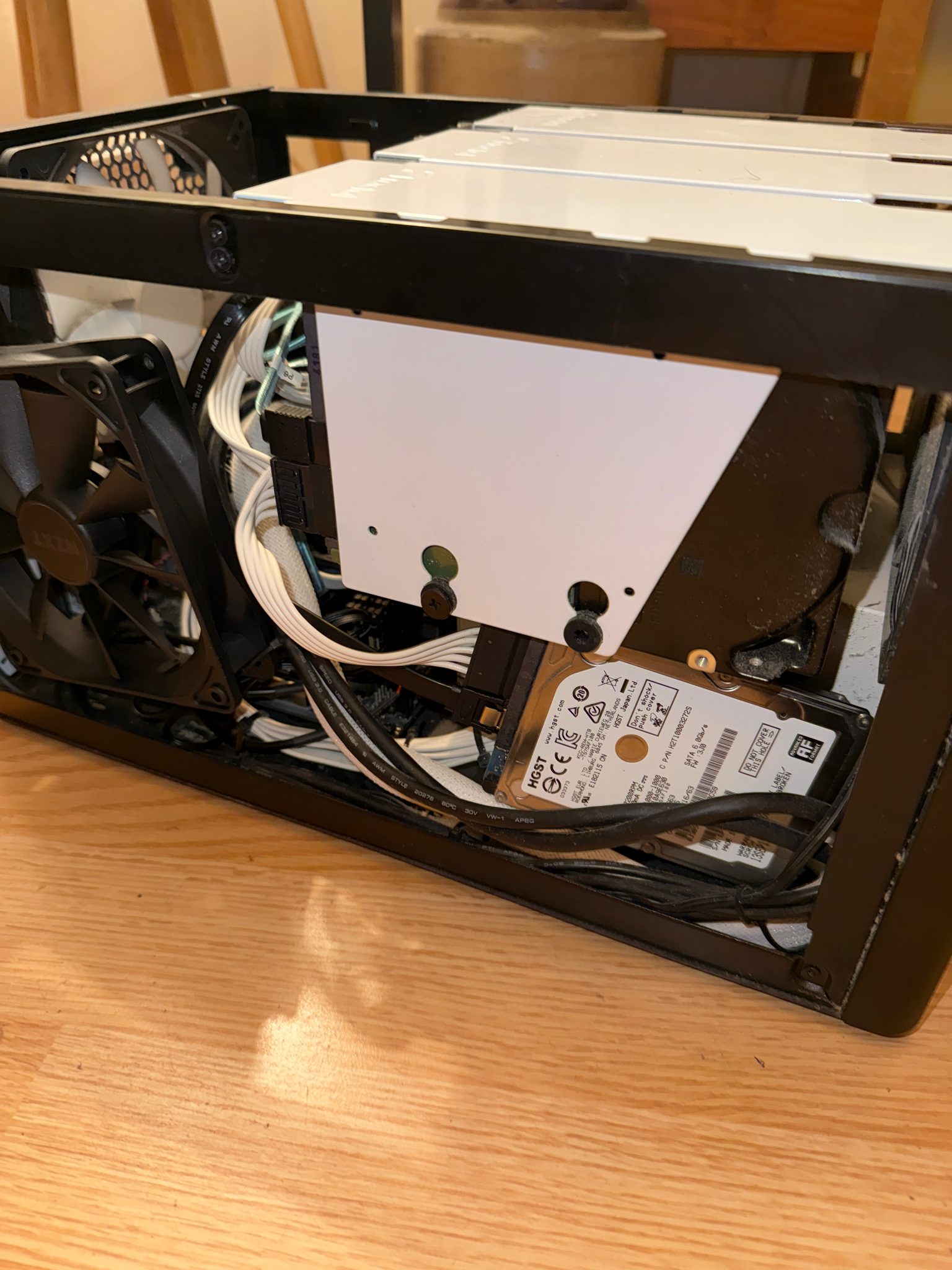 Inside the home server, with stacked drive cages, a 2.5-inch HGST drive, and an NZXT fan